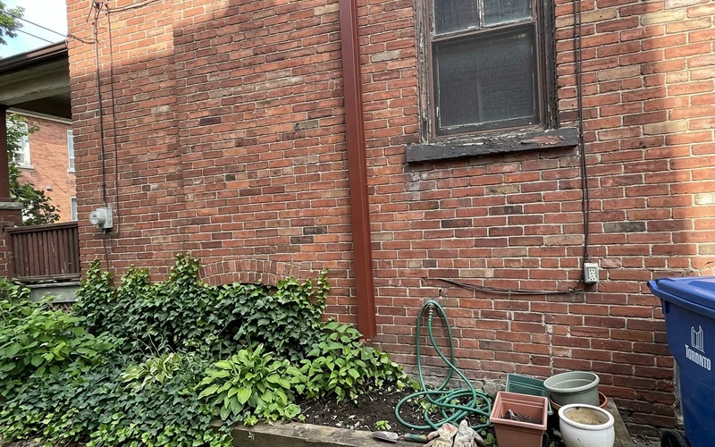 Exterior line hide running up a brick wall to a second-floor ductless head