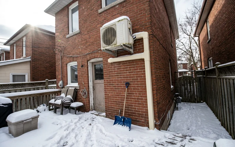 Mini-split outdoor unit on a wall bracket above the snow line with a line hide cover