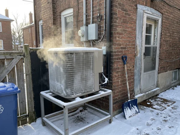 Air-source heat pump defrosting with light steam on a winter morning