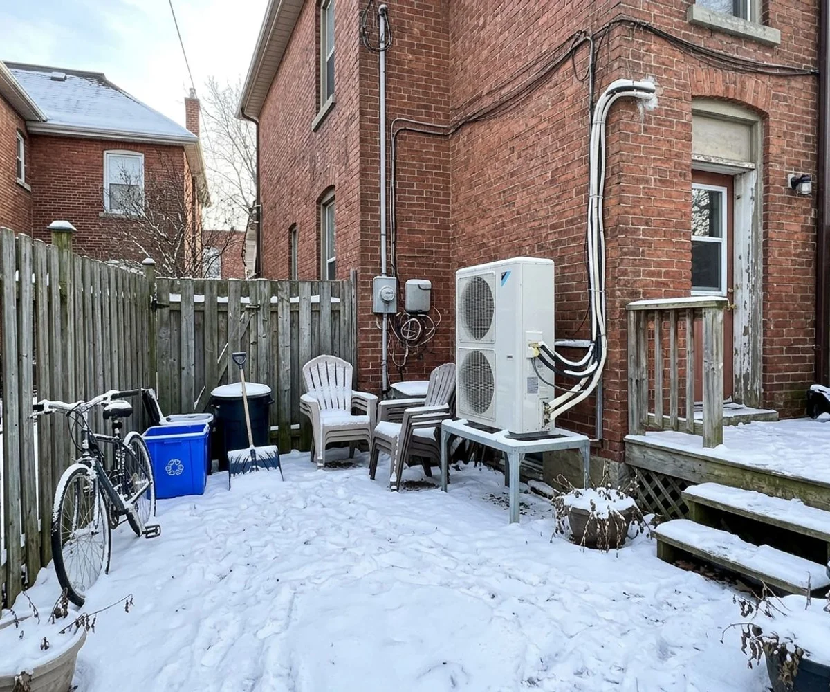 Mitsubishi Hyper-Heat multi-zone outdoor unit on a raised stand behind a Cabbagetown row house